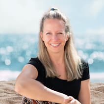 Marloes Mulder, expert in Hashimoto klachten en trage schildklier vermoeidheid zit glimlachend buiten aan het strand bij zee