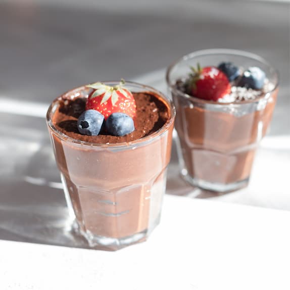 Twee glazen chocolademousse met bessen symboliseren optimalisatie van het dieet voor afvallen, herstel en meer energie bij Hashimoto en trage schildklier