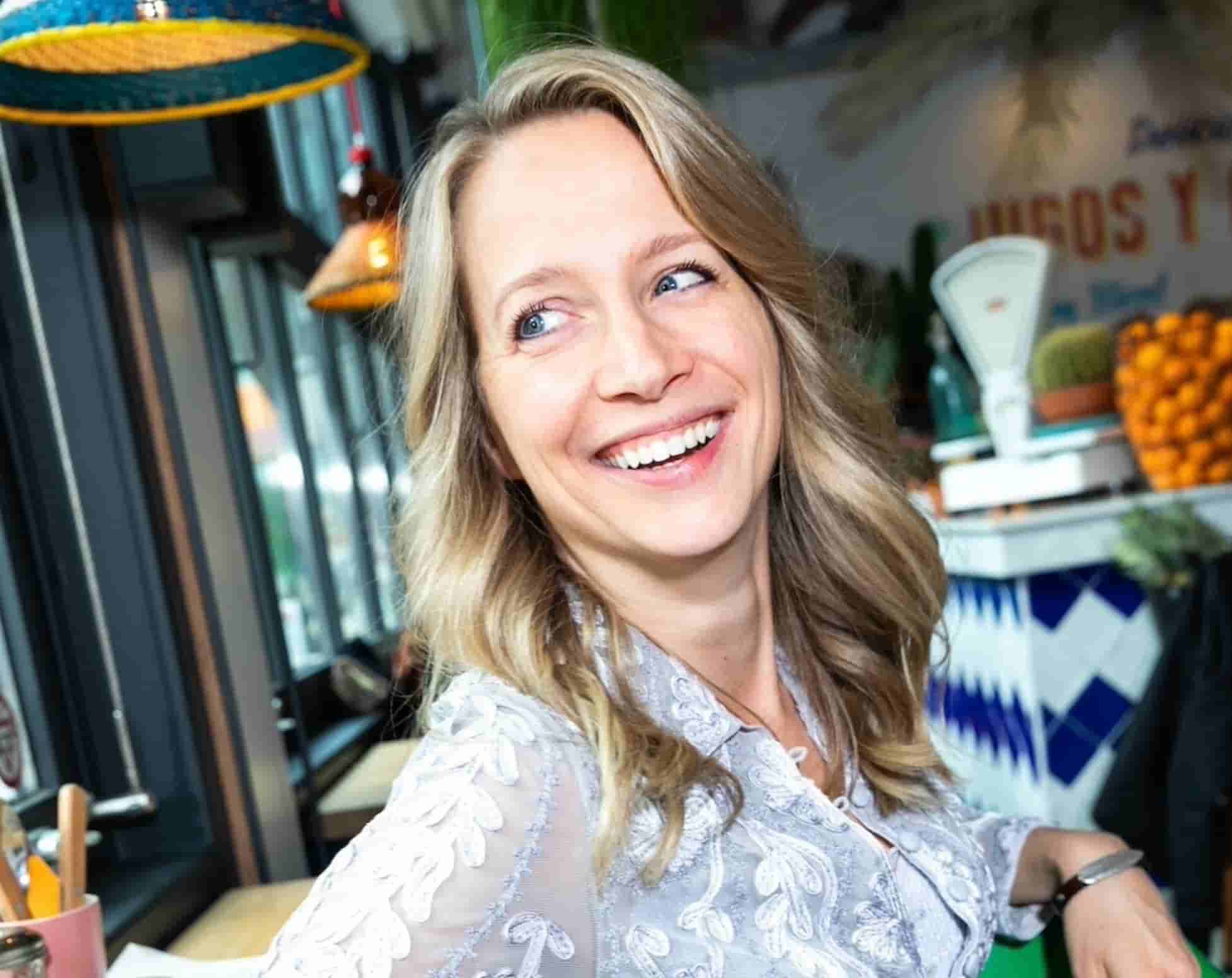 Marloes Mulder, expert in Hashimoto en trage schildklier, lachend tijdens een consult in een lichte setting.